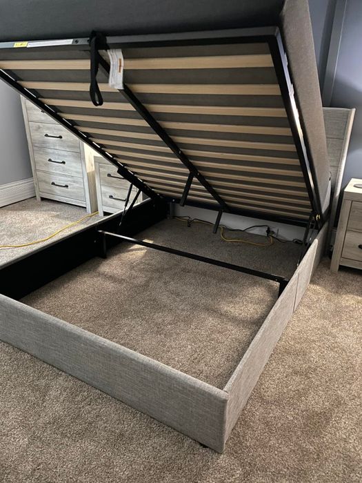 A photo of a bed frame with an accessible storage compartment beneath, highlighting the lifting mechanism for the mattress