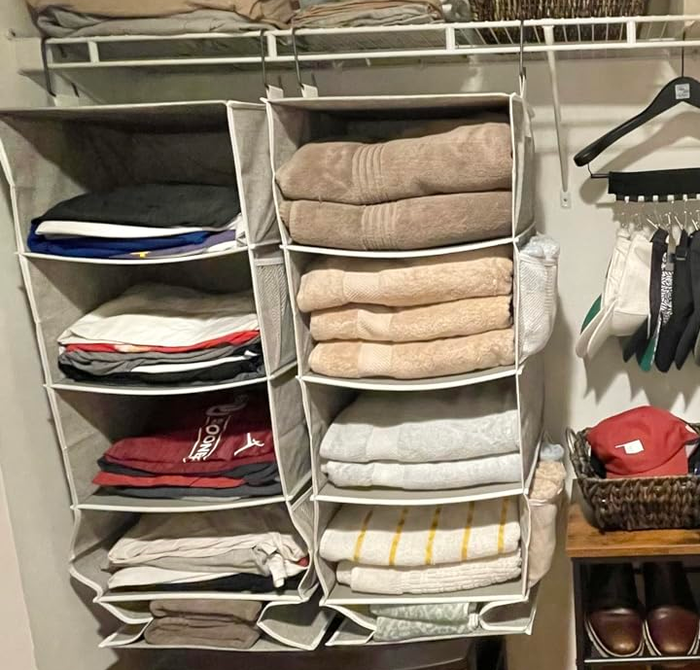 A neatly organized closet featuring folded clothes, shoes in cubbies, hats on shelves, hanging shorts, pants, shirts, and baskets for additional storage