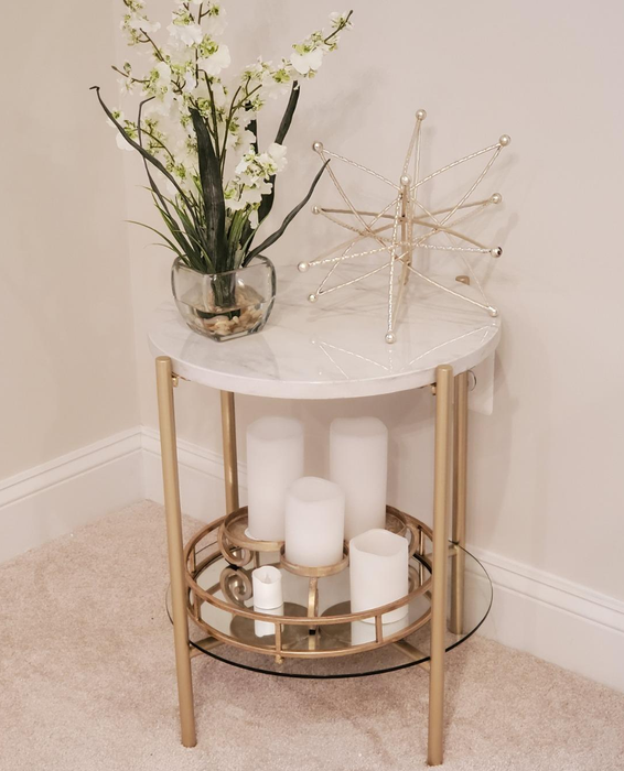 A reviewer’s photo of the marble and gold end table, decorated with flowers and candles.