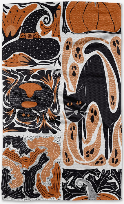 a black, white, and orange tea towel adorned with various Halloween-themed designs, such as a witch's hat, a black cat, pumpkins, and bats