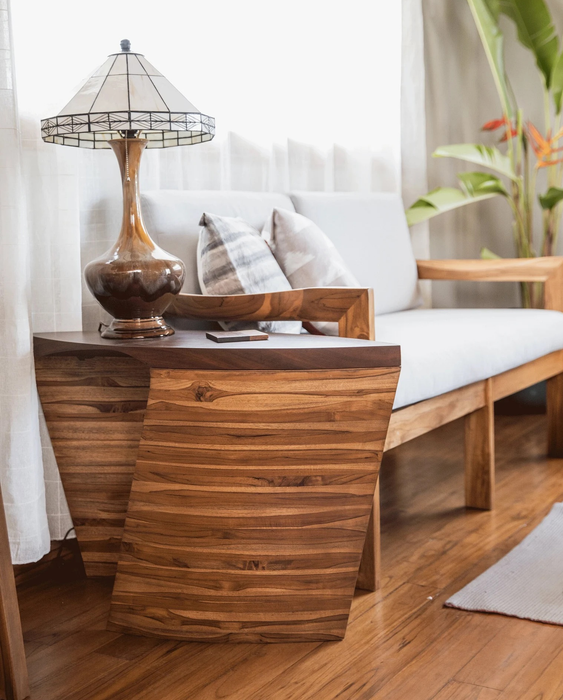 The wooden side table featuring a lamp and a coaster, placed next to a couch.