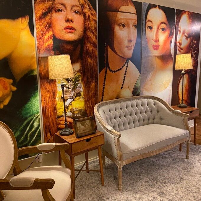 a reviewer photo of the loveseat positioned in front of stunning artwork