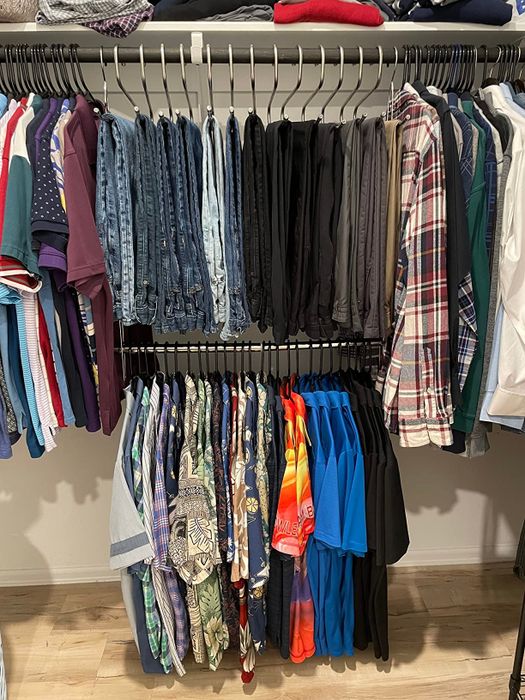 A closet displaying neatly hung clothes, including shirts, jeans, and pants on hangers