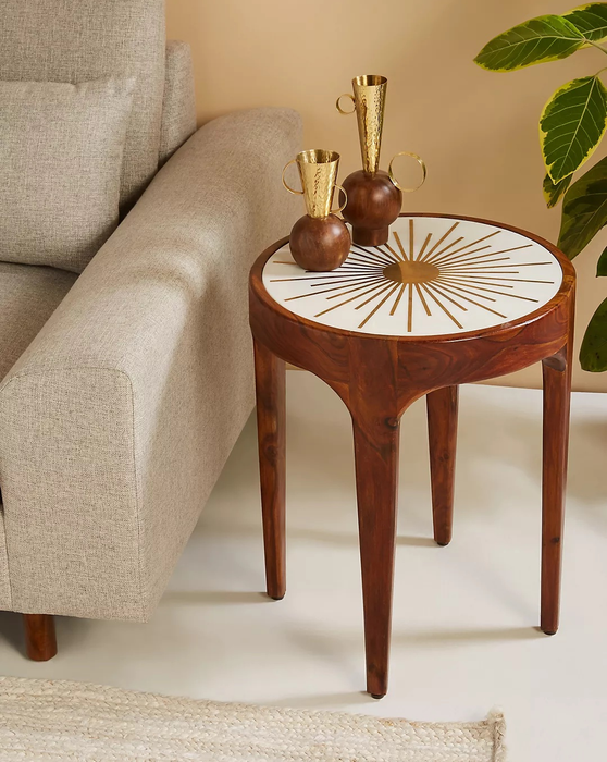 The starburst side table holding a few trinkets next to a sofa.