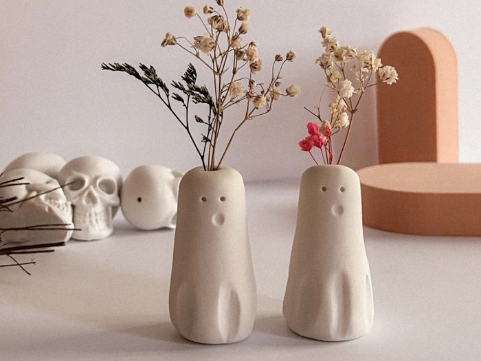 two dainty minimalist ghost vases with small flower stems sprouting from the tops