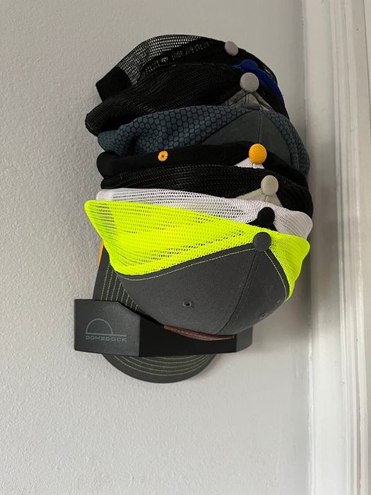 Baseball caps, including a bright neon green one, hanging neatly on a wall-mounted hook