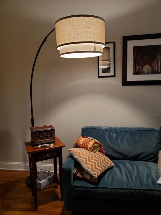 The floor lamp featuring a large arch, a round base, and a spacious drum-shaped lampshade hanging gracefully.