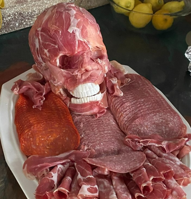 the skull lavishly covered with prosciutto atop a platter of meats