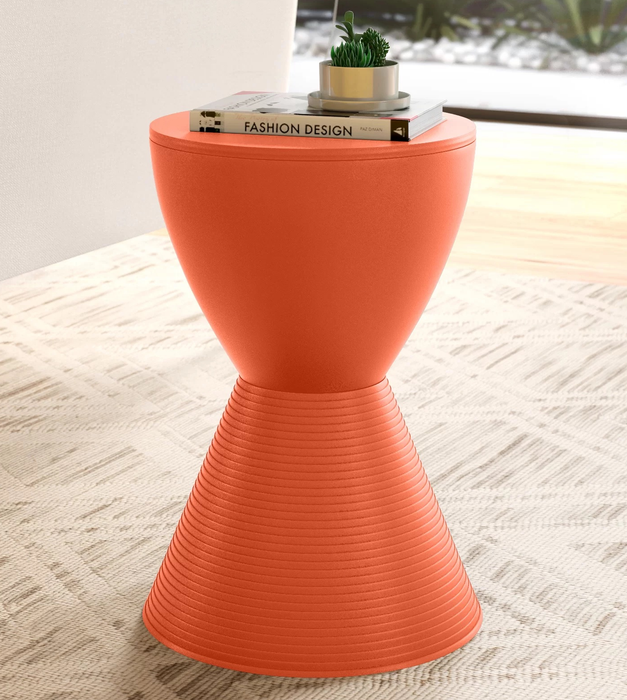 The orange table holding a book and a small plant.