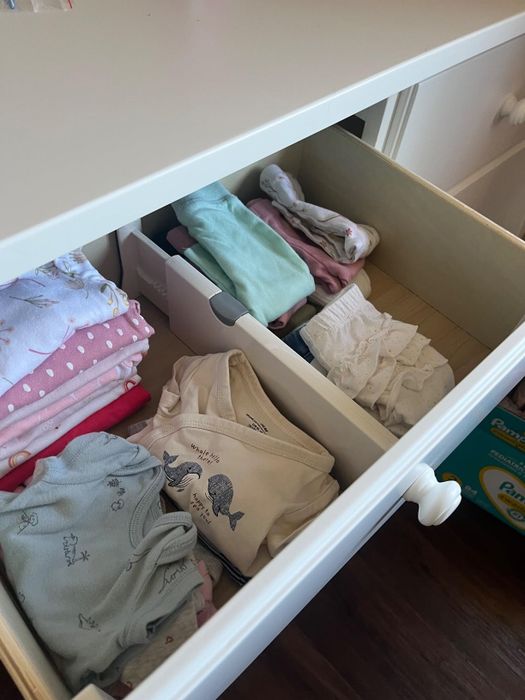 An open drawer showcasing neatly arranged baby clothes, including folded onesies and pajamas