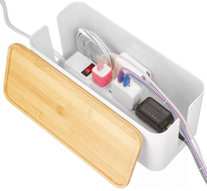 A cable organization box with a wooden lid, neatly containing various plugs and cords inside.