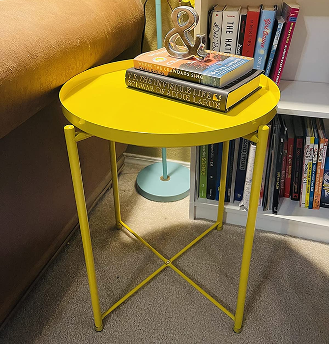 Reviewer photo of the yellow table holding books next to an armchair and bookshelf.
