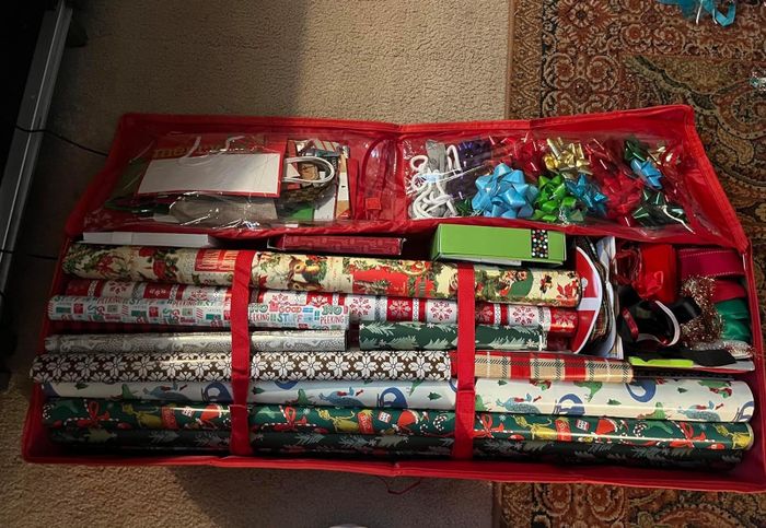 a reviewer's red storage bag packed with wrapping paper, gift bags, ribbons, and bows