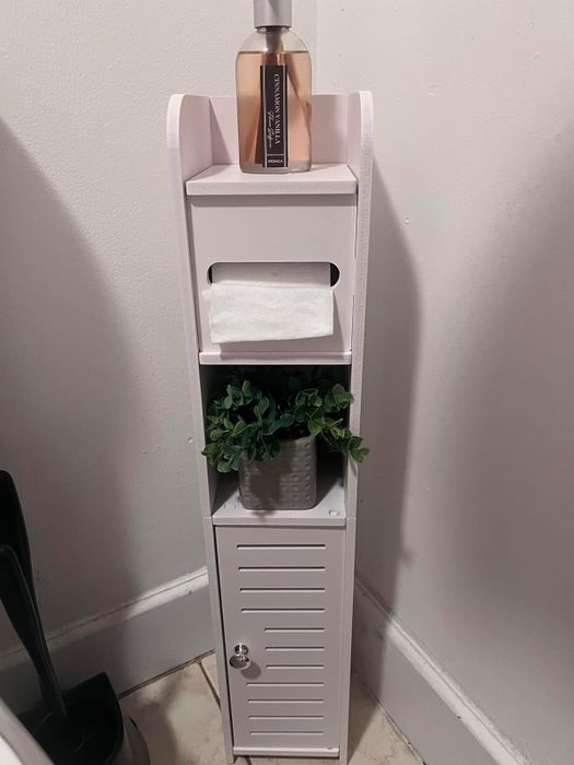 A sleek bathroom storage solution showcased by a reviewer, featuring a hidden toilet paper roll and a discreet cabinet.