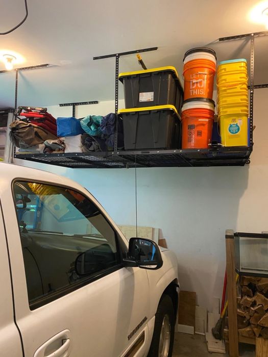A reviewer’s black shelving unit loaded with various buckets, storage containers, and camping gear.
