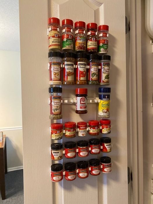 A reviewer’s white spice rack mounted on the inside of a closet door, filled with various spices.