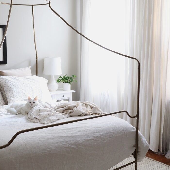 a reviewer’s gold canopy bed dressed in white linens