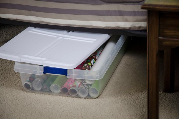 a plastic under-bed storage container filled with wrapping paper