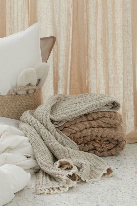 a neatly stacked pile of neutral-toned throw blankets