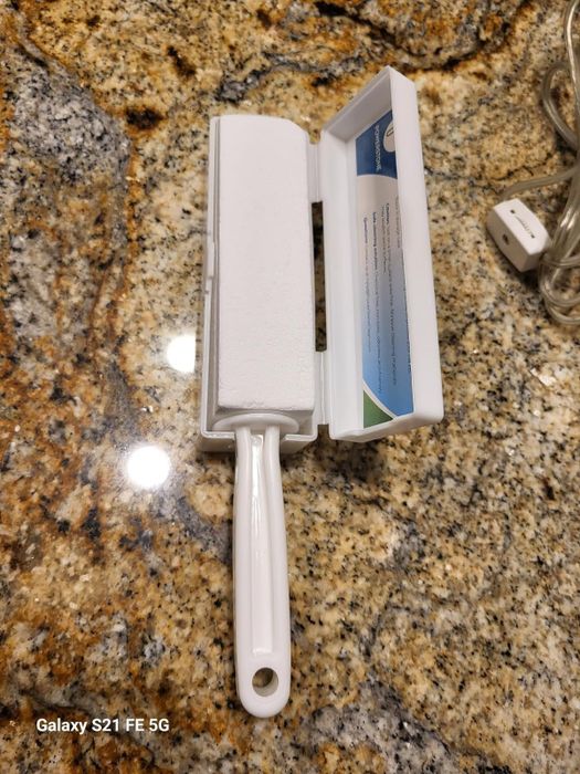 A cleaning tool with a white handle, placed next to its open storage case on a granite countertop