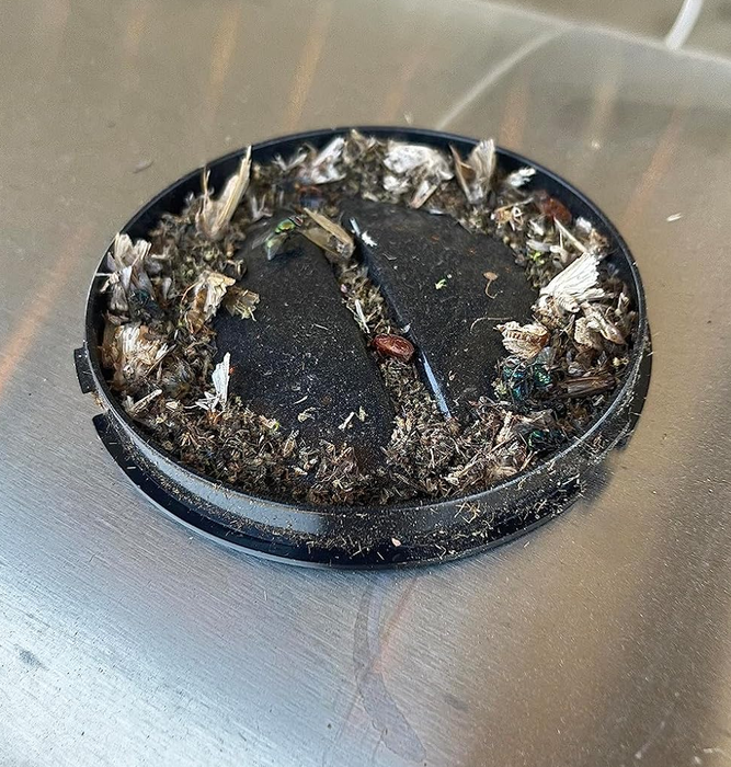 An ashtray filled with cigarette butts on a metal surface