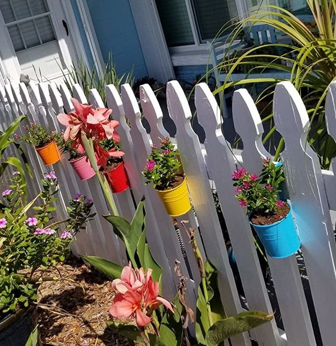 a reviewer’s photo showing colorful planters hanging on a white picket fence