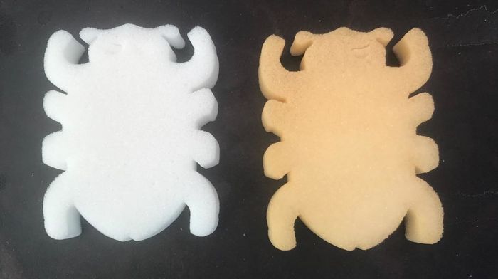 A clean white bug-shaped sponge next to one that's slightly tinged with orange