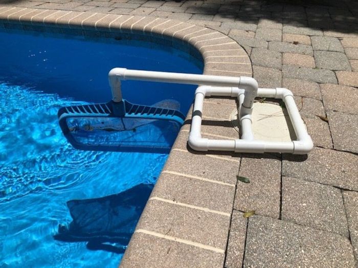 A pipe base holding a skimmer net along the pool's surface