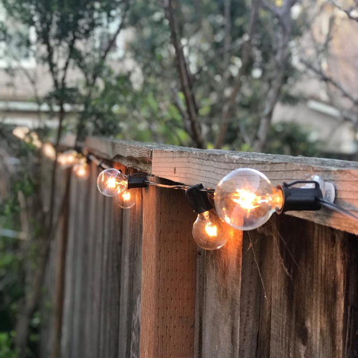 A close-up of the illuminated string lights fastened to a wooden fence.