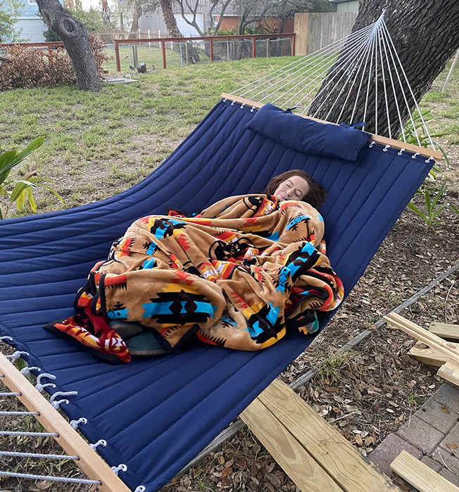 Reviewer cozied up in a blanket on the blue hammock.