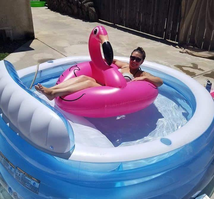 Reviewer floating on a flamingo floatie in an inflatable pool.