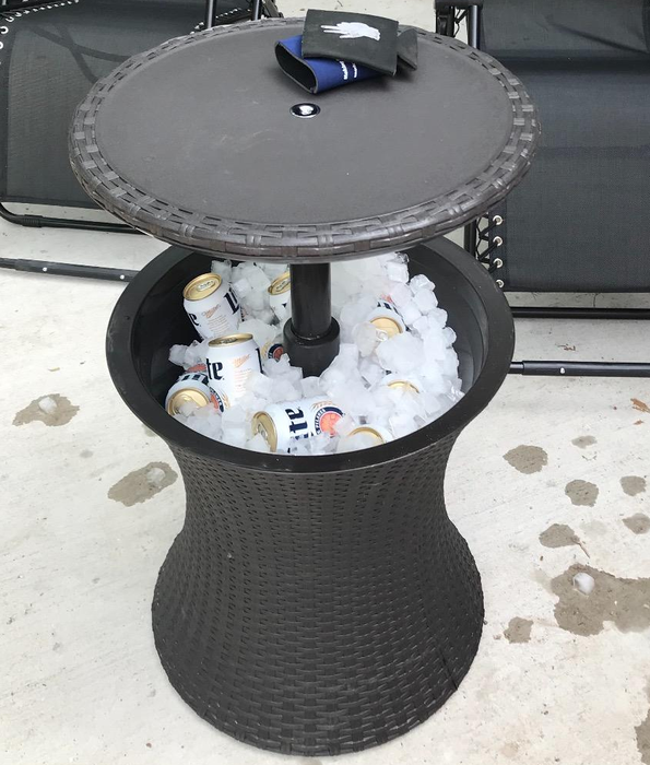 The side table cooler filled with ice and cans of beer, ready to chill.