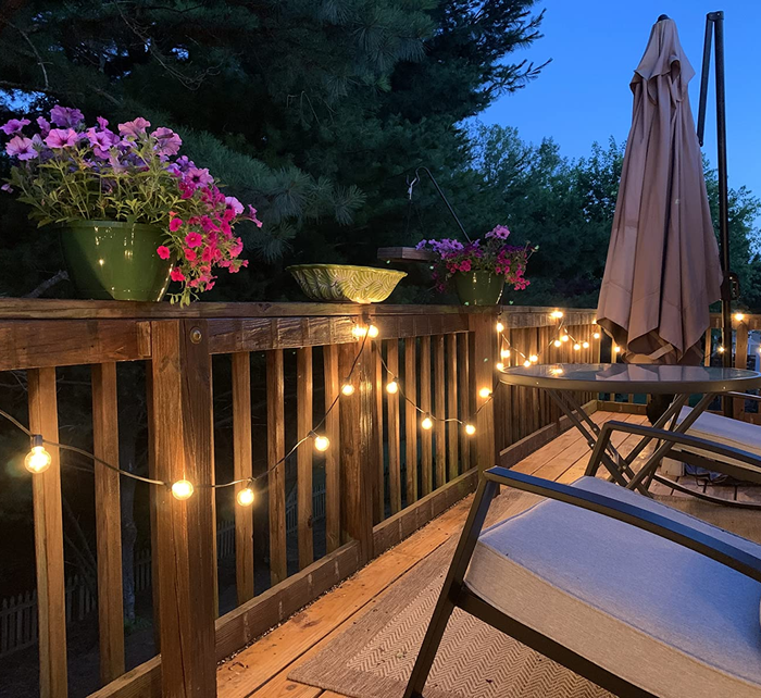 The string lights glowing at night, attached to a wooden deck railing.