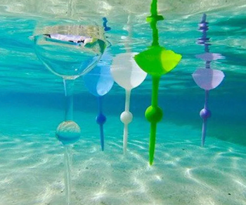 An underwater shot of wine glasses drifting in a pool, gently floating along.
