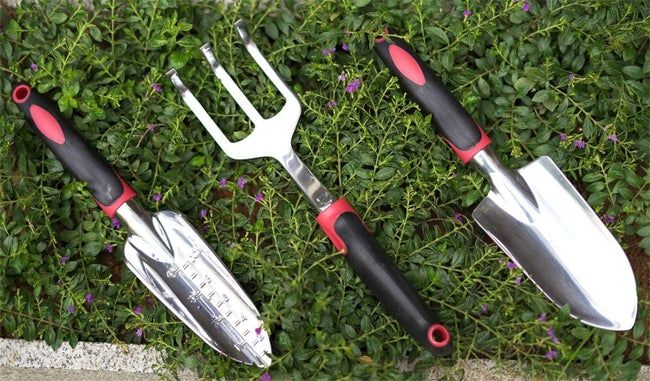 The two trowels and hand rake placed in the grass