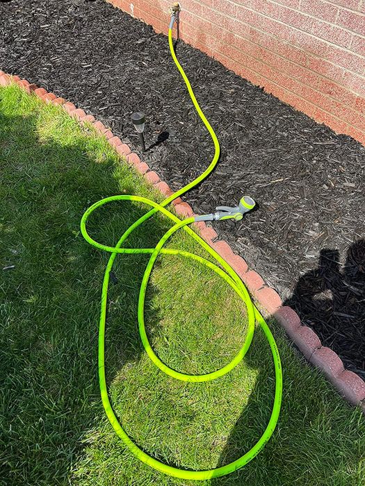 A reviewer's bright lime green garden hose in use