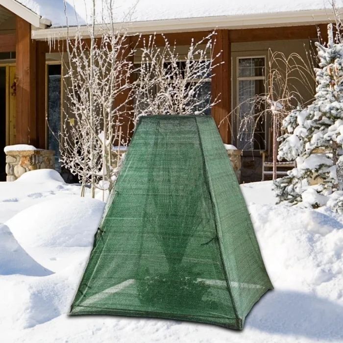 Green cover shielding a bush from snow
