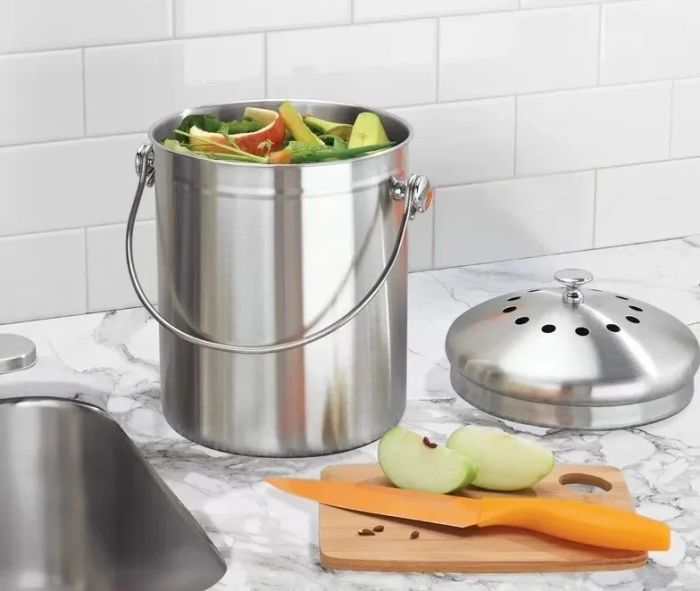 A composter placed on a countertop, filled with fruit scraps.
