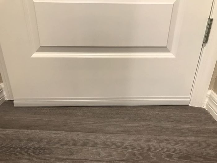 close-up of the same door with a white Suptike door draft stopper installed to close the gap at the bottom
