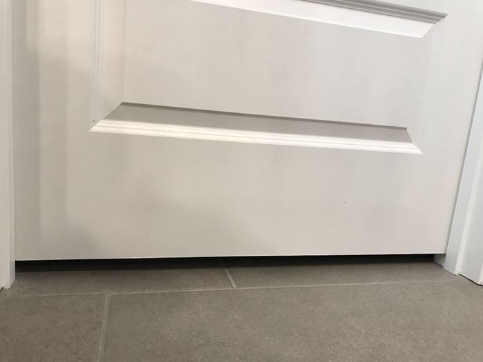 close-up of a reviewer image showing a large gap between the bottom of a white door and the floor below