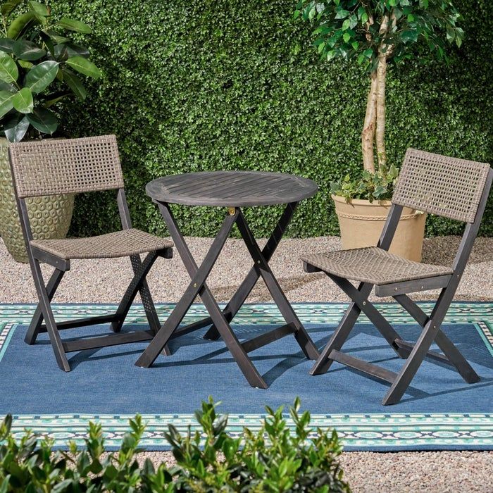 A grey-stained wooden outdoor table and chair set resting on a blue rug, perfect for enjoying the outdoors.