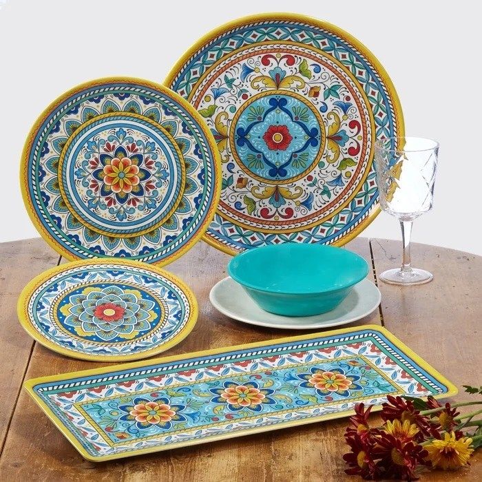 Blue and yellow patterned plates and bowls set on a wooden table, perfect for outdoor dining.