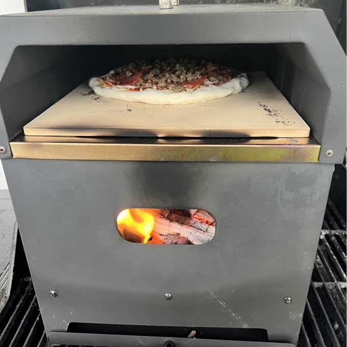 The pizza oven cooking a pizza on the grill, turning it into a delicious masterpiece.