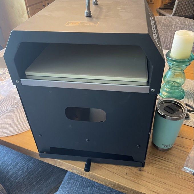 A pizza oven sitting idle on a table, awaiting its turn to cook.