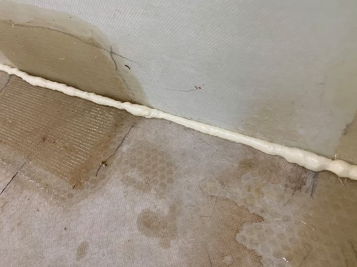 Reviewer image showing foam sealant filling the gap between the wall and floor