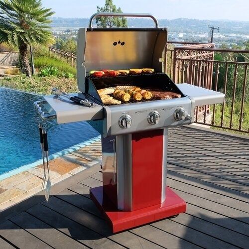 An open grill next to a pool, sizzling food as it cooks on a sunny day.