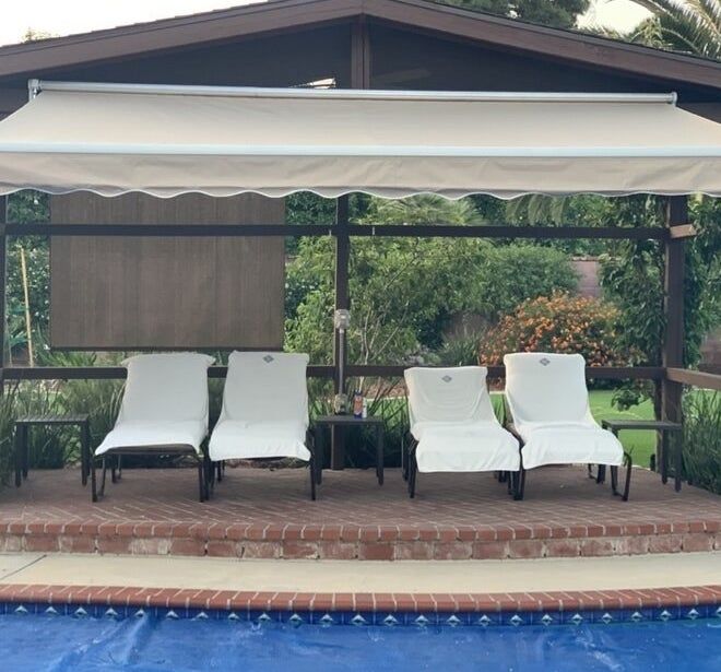 A retractable awning providing shade for four chairs placed near a pool, offering relief from the sun.