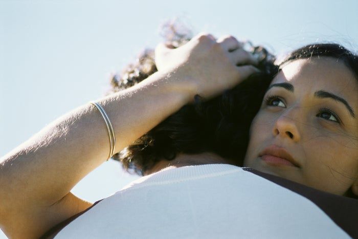 A couple sharing a tender moment, with one person resting their head on the other's shoulder, both looking at peace