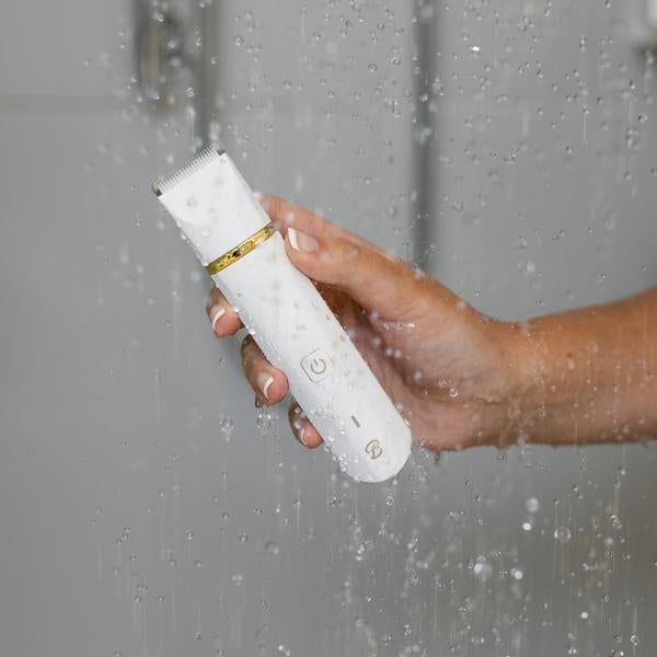 A model holding a white trimmer while in the shower