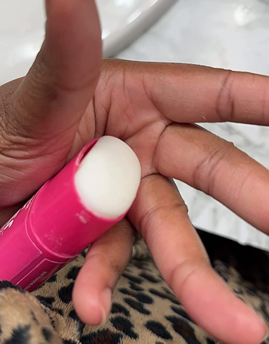 Reviewer holding a pink tube, revealing the white balm inside